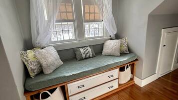 A cozy room with a built-in bench, a window with sheer curtains, and a door.
