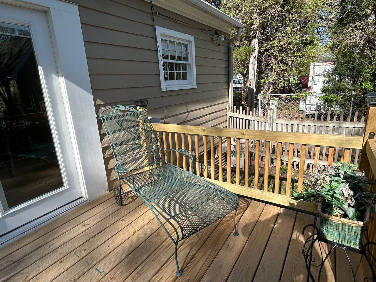Une terrasse en bois avec un banc en métal et un panier en osier.