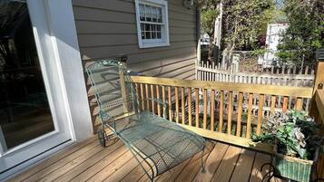 Une terrasse en bois avec un banc en métal et un panier en osier.