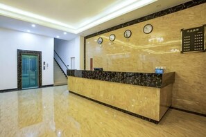 A hotel reception area with a marble counter, clocks, and a staircase. - Fenglinge Hotel (Zhangjiajie)