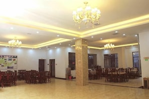 A spacious hall with multiple chandeliers, a central pillar, and rows of chairs.