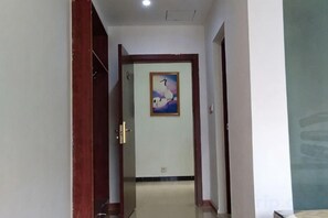 A hallway with a wooden door, a framed picture on the wall, and a tiled floor. - Fenglinge Hotel (Zhangjiajie)