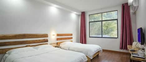 Una habitación con dos camas, un escritorio, una computadora y un ventanal con cortinas.