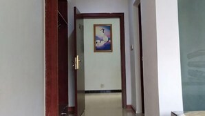 Un pasillo con una puerta de madera, un cuadro enmarcado en la pared y piso de baldosas.