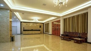 Un hall d’hôtel comprenant un comptoir d’accueil, un espace salon et un lustre.