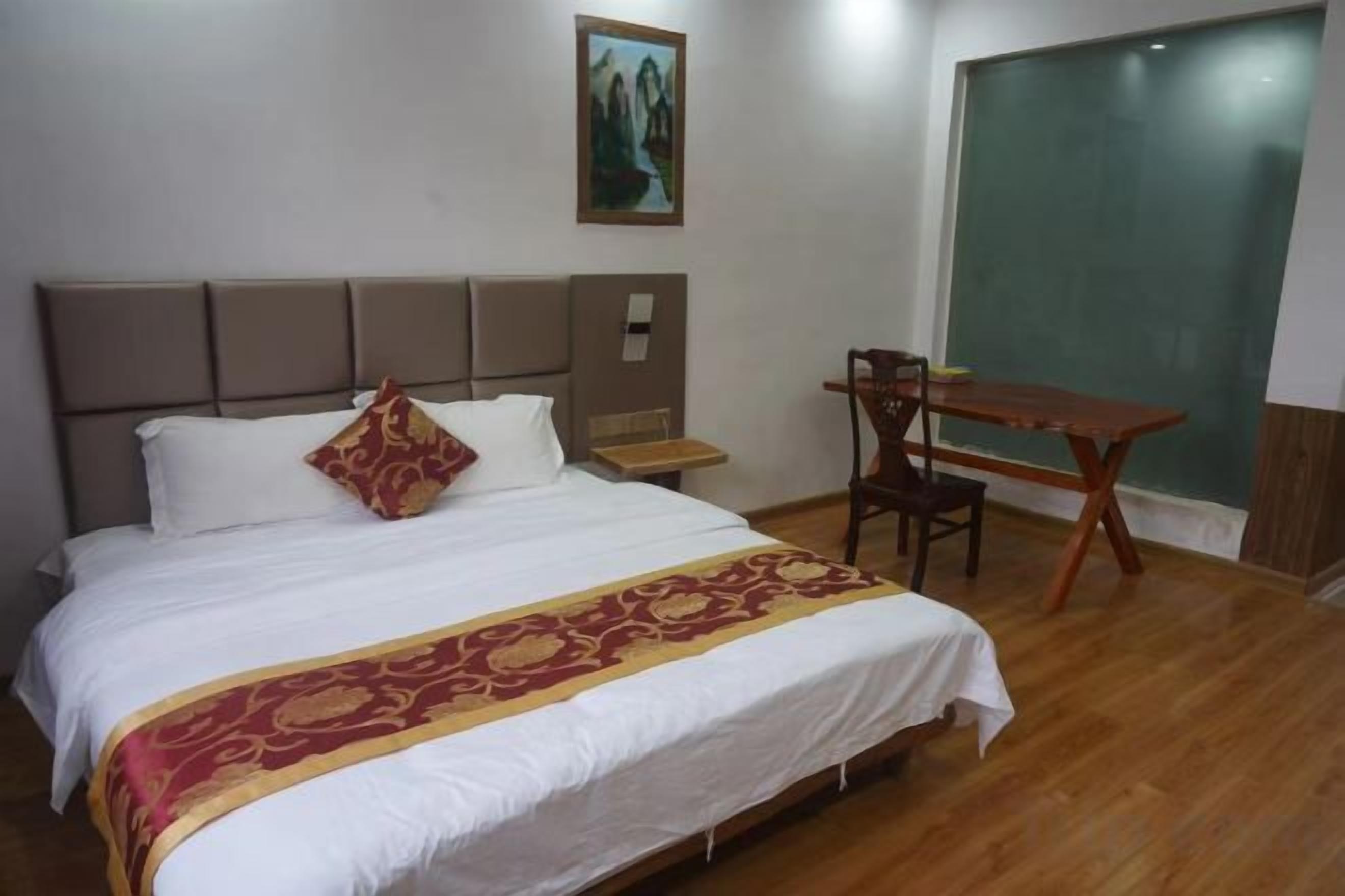 A hotel room with a bed, a desk, a chair, and a large window.
