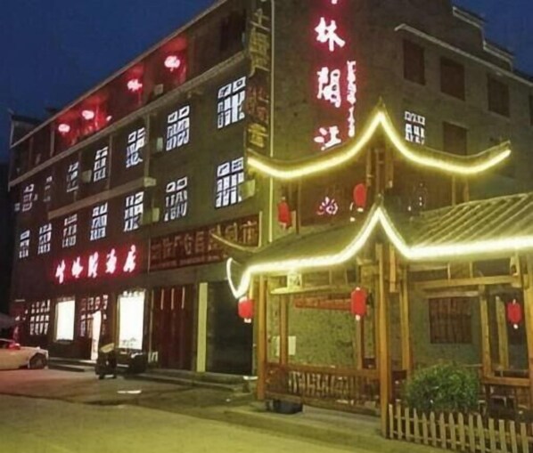 A traditional building with illuminated signage, a wooden entrance, and a picket fence.