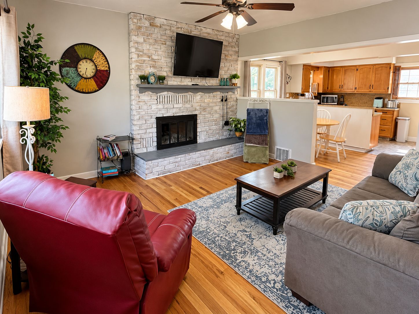 A living room with a fireplace, a television, and a dining area with a kitchen in the background.
