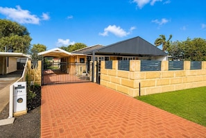 A residential property with a paved driveway, a gated entrance, and a brick wall.