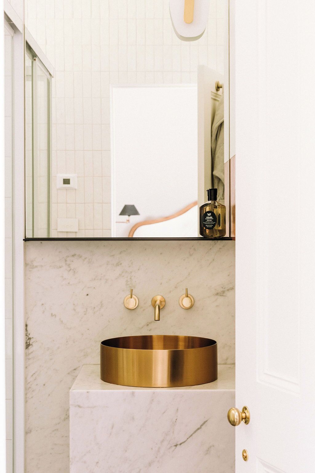 Un baño con lavamanos dorado, encimera de mármol y un espejo encima.