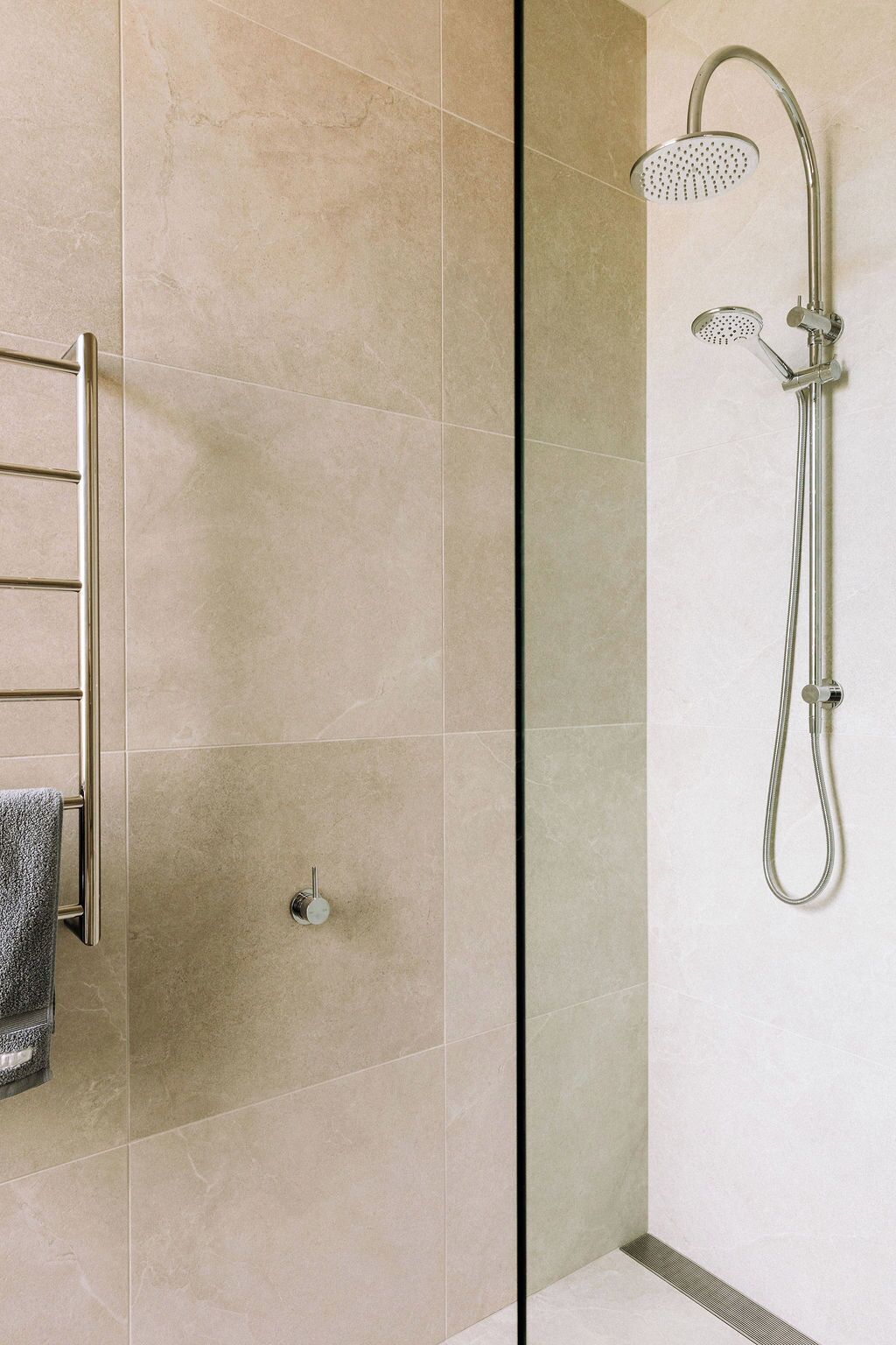 Une salle de bain moderne avec une douche à parois de verre, un porte-serviettes et une douchette à main.