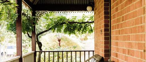A wooden porch with wicker furniture and a brick wall.