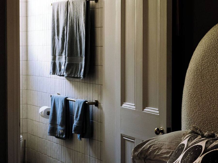 Un baño con toallero, dispensador de papel higiénico y una puerta con picaporte.