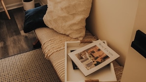 A cozy room with a bed, a potted plant, and a magazine on the bed.