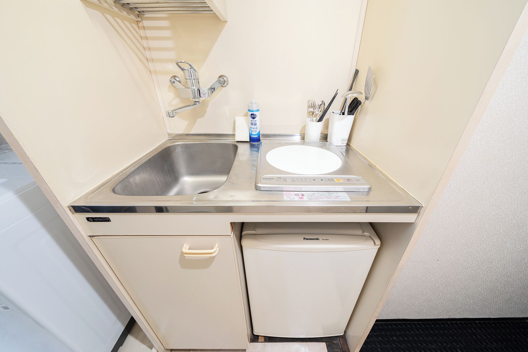 A compact kitchenette with a sink, a dish drying mat, a small refrigerator, and a microwave.