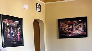 Un comedor con una mesa y sillas de madera, una escalera con barandillas blancas y dos cuadros en la pared.