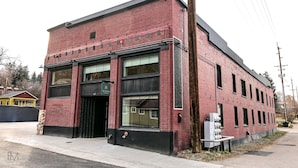 A red brick building with large windows and a black awning. - Stanley Theme: Suites of Lava #11 (Lava Hot Springs)