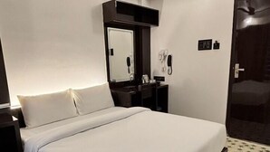 A hotel room with a bed, a ceiling fan, a mirror, a telephone, and a door. - LUXESTYLE (Adoor)