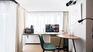 A compact hotel room with a kitchenette, a flat-screen TV, a green chair, and a small table. - Excellent access to Shibuya area! Residence with cherry blossom motif [307]. (Meguro-ku)