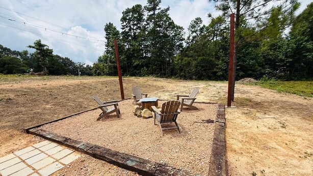 An outdoor seating area with a table and chairs, surrounded by a wooden fence and trees in the background. - The Last Resort

 No pets allowed (Kirby)