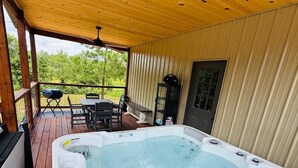A hot tub on a wooden deck with a table and chairs, surrounded by a wooden fence and a metal door. - The Last Resort

 No pets allowed (Kirby)