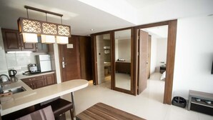 A modern kitchen with a built-in oven, a dining area with a bench, and a sliding door leading to a bathroom. - Sanya Xintai Ocean View Hotel (Sanya)