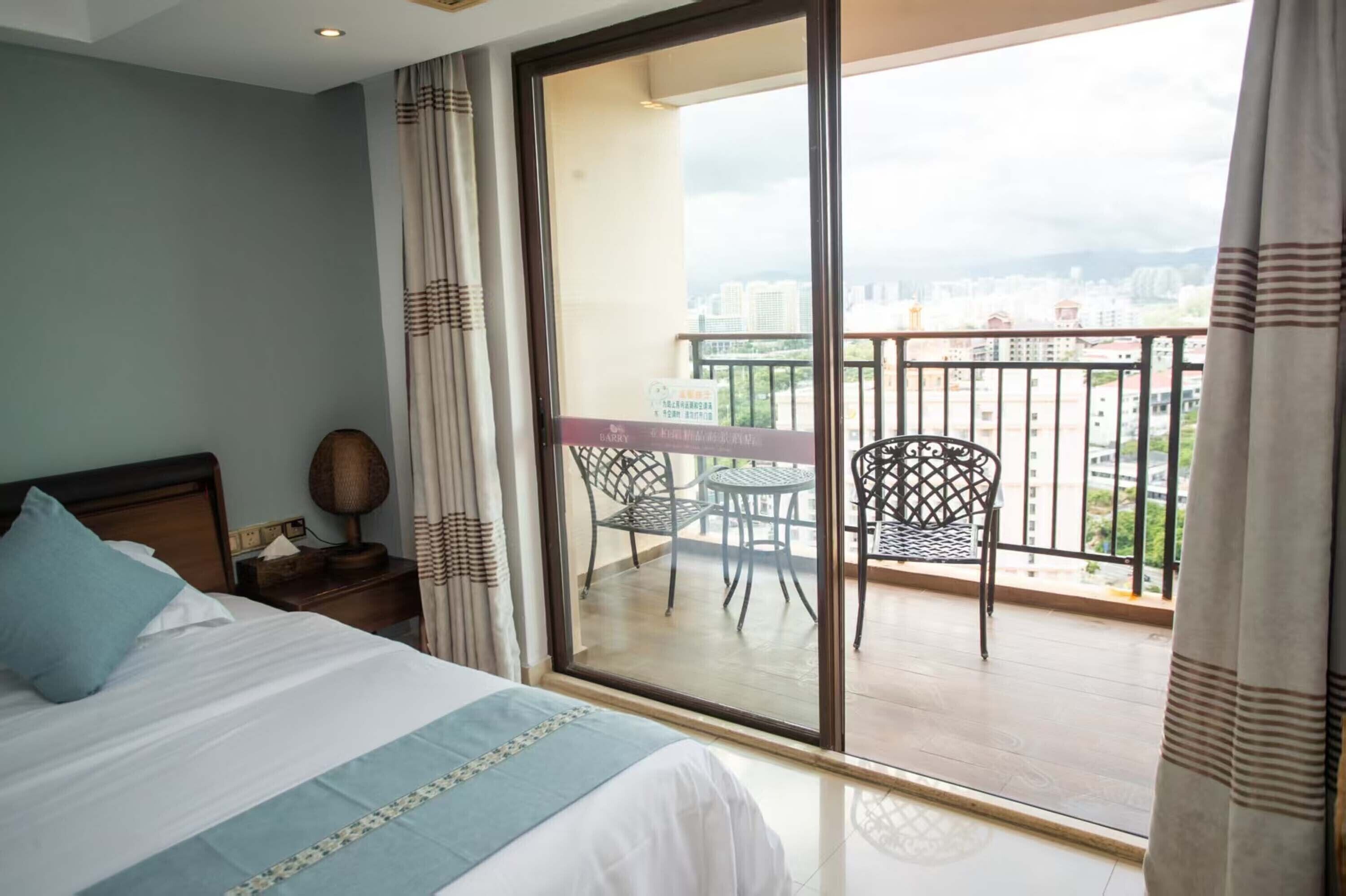 A hotel room with a large bed, a small table, and a balcony with chairs.