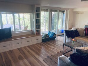 A spacious living room with a large window, built-in bookshelf, and a comfortable seating area.