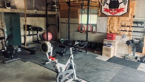 A gym with various exercise equipment, including a stationary bike, weight bench, and resistance bands. - A restful stay in Georgian Bluffs (Georgian Bluffs)