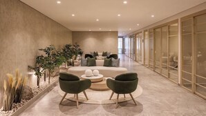 A modern lounge area with a curved sofa, two green armchairs, and a round coffee table.