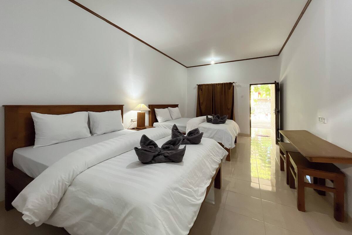 Una habitación de hotel con dos camas, cabecera de madera, un escritorio y un televisor.