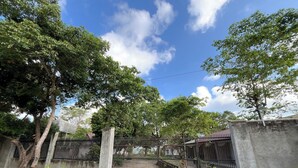 A gated entrance with a concrete wall and metal fence, surrounded by trees and a clear sky. - Bara Cabana Hotel (Bira)