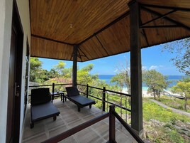 Un espacio de descanso techado al aire libre con sillones y vista al océano.
