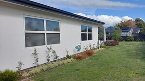 A modern house with a well-maintained lawn, a decorative bird sculpture, and a fenced yard. - Kotuku - a quiet retreat in lovely Mapua (Māpua)