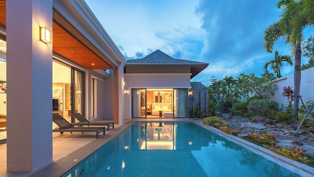 Una casa moderna con piscina, ventanas amplias y un jardín cuidado.