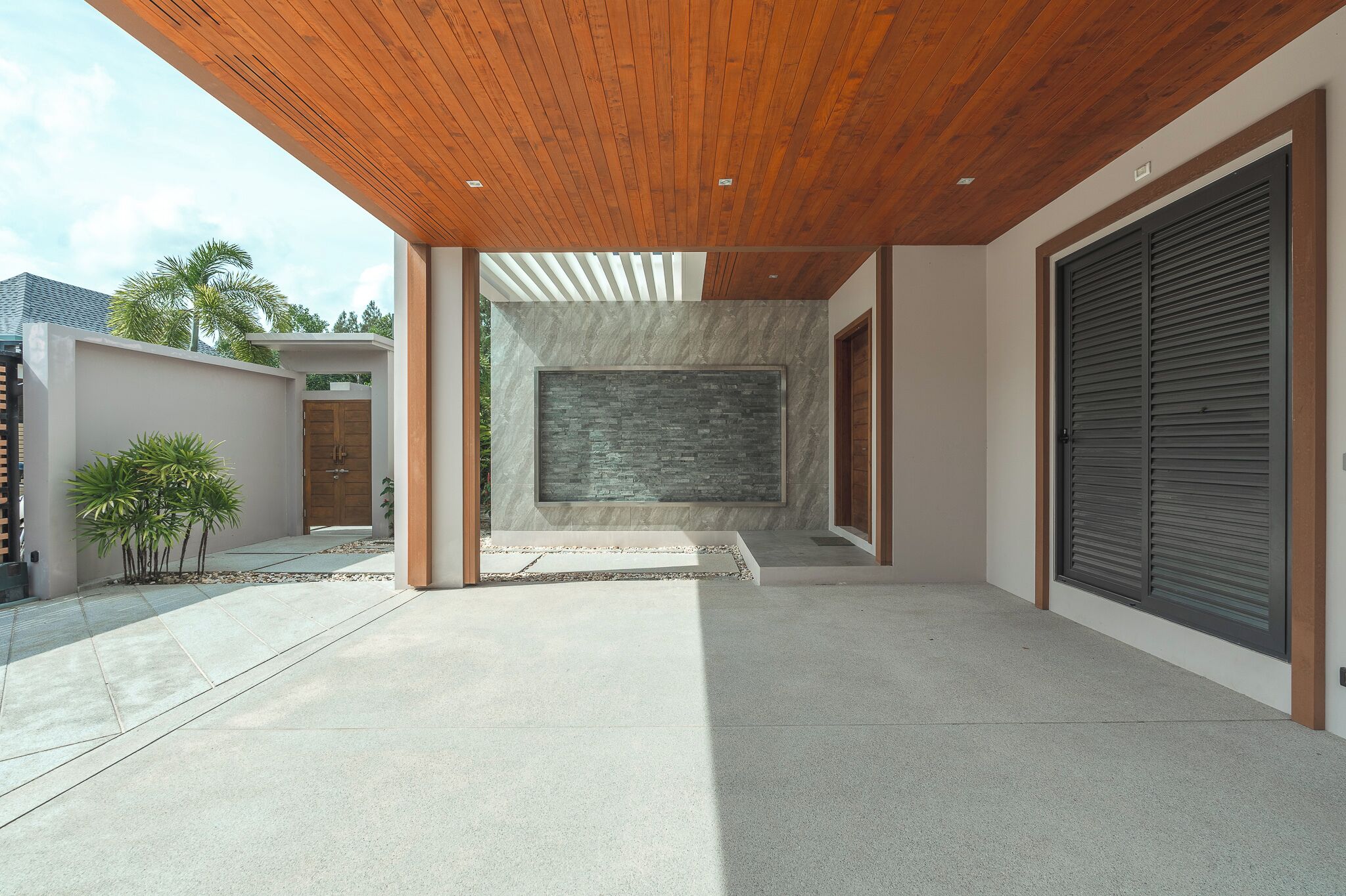 A modern building with a concrete floor, a wooden ceiling, and a large stone wall.