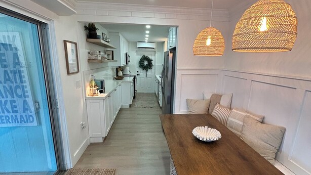 A modern kitchen with white cabinets, a wooden dining table, and hanging wicker lamps. - Key Largo 3 bedroom 2 bathroom home with spacious lot for boat/RV parking (Key Largo)