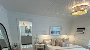 A bedroom with a large bed, bedside tables, a mirror, and a ceiling light fixture. - Key Largo 3 bedroom 2 bathroom home with spacious lot for boat/RV parking (Key Largo)