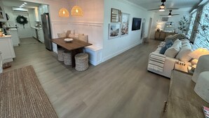 A spacious living room with a large sofa, a dining area with a wooden table, and a kitchen in the background. - Key Largo 3 bedroom 2 bathroom home with spacious lot for boat/RV parking (Key Largo)