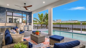 Un patio con mobiliario exterior, una parrilla y vistas a una piscina.
