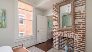 A room with a brick fireplace, a large window, and a door.