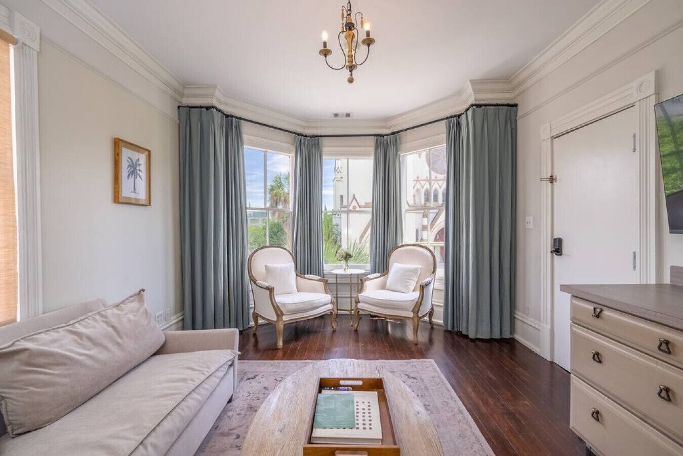 Una habitación amplia con un gran ventanal, dos sillones, un sofá y una mesa de centro de madera.