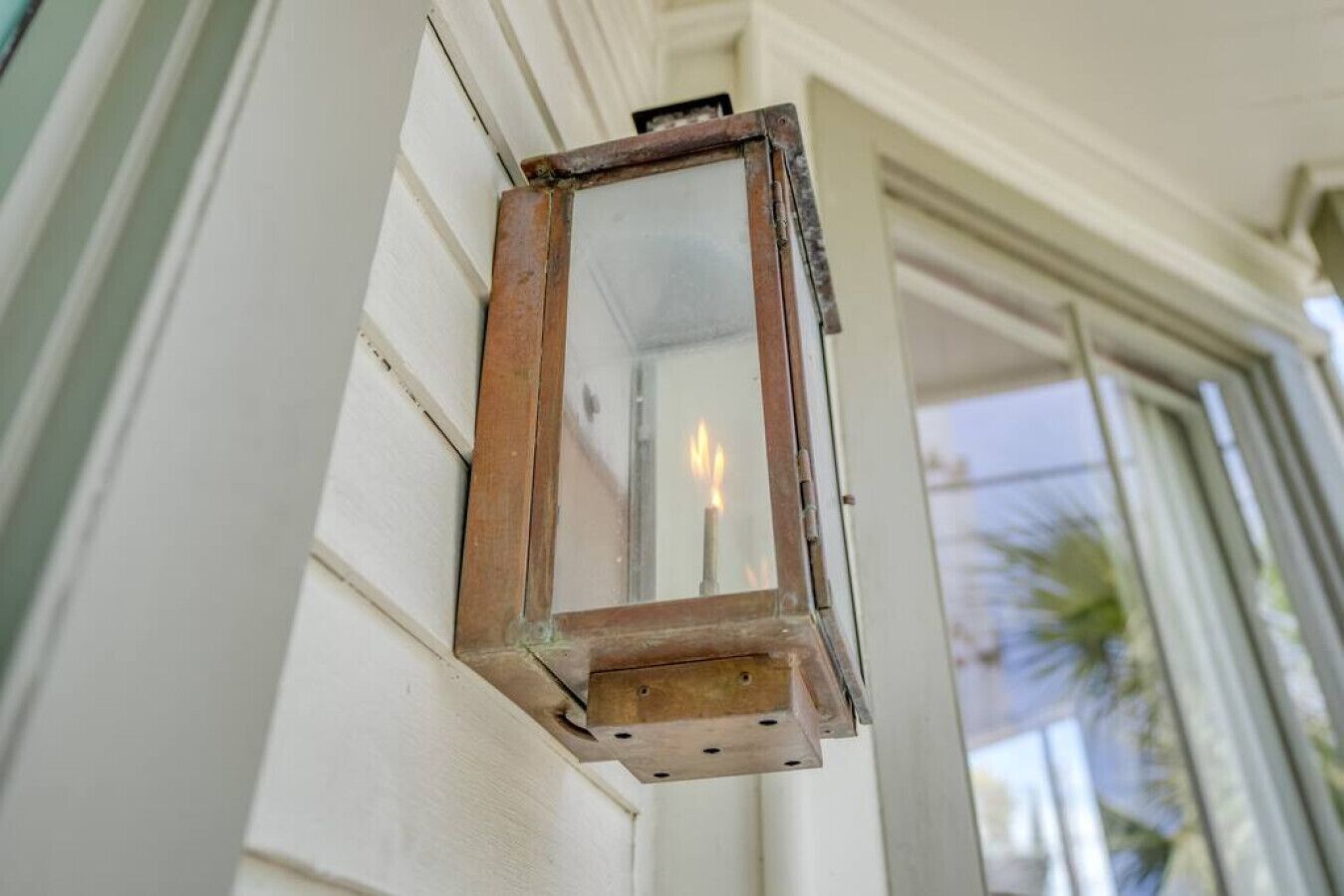 A weathered lantern hanging on a white exterior wall.