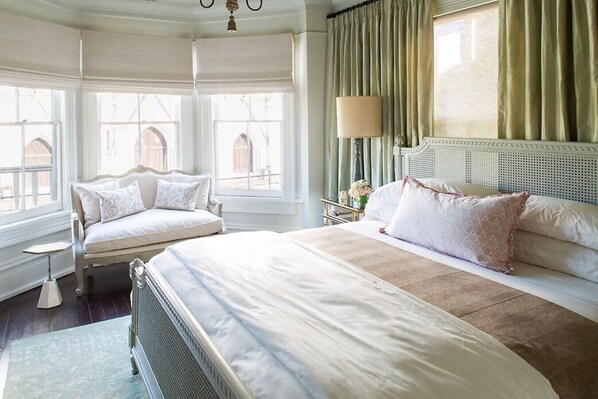 Ein Schlafzimmer mit einem großen Bett, einer Liege und einem Fenster mit Vorhängen.