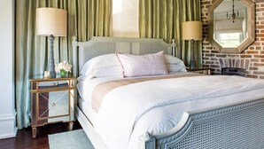 A neatly made bed with a headboard, two bedside tables with lamps, and a large mirror on the wall.