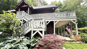 Una casa de madera con un balcón y escaleras que llevan a un porche cubierto.