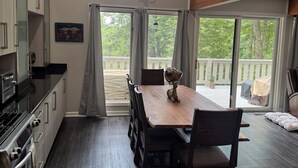 Una cocina amplia con comedor, ventanas grandes y una escalera que sube a un nivel superior.
