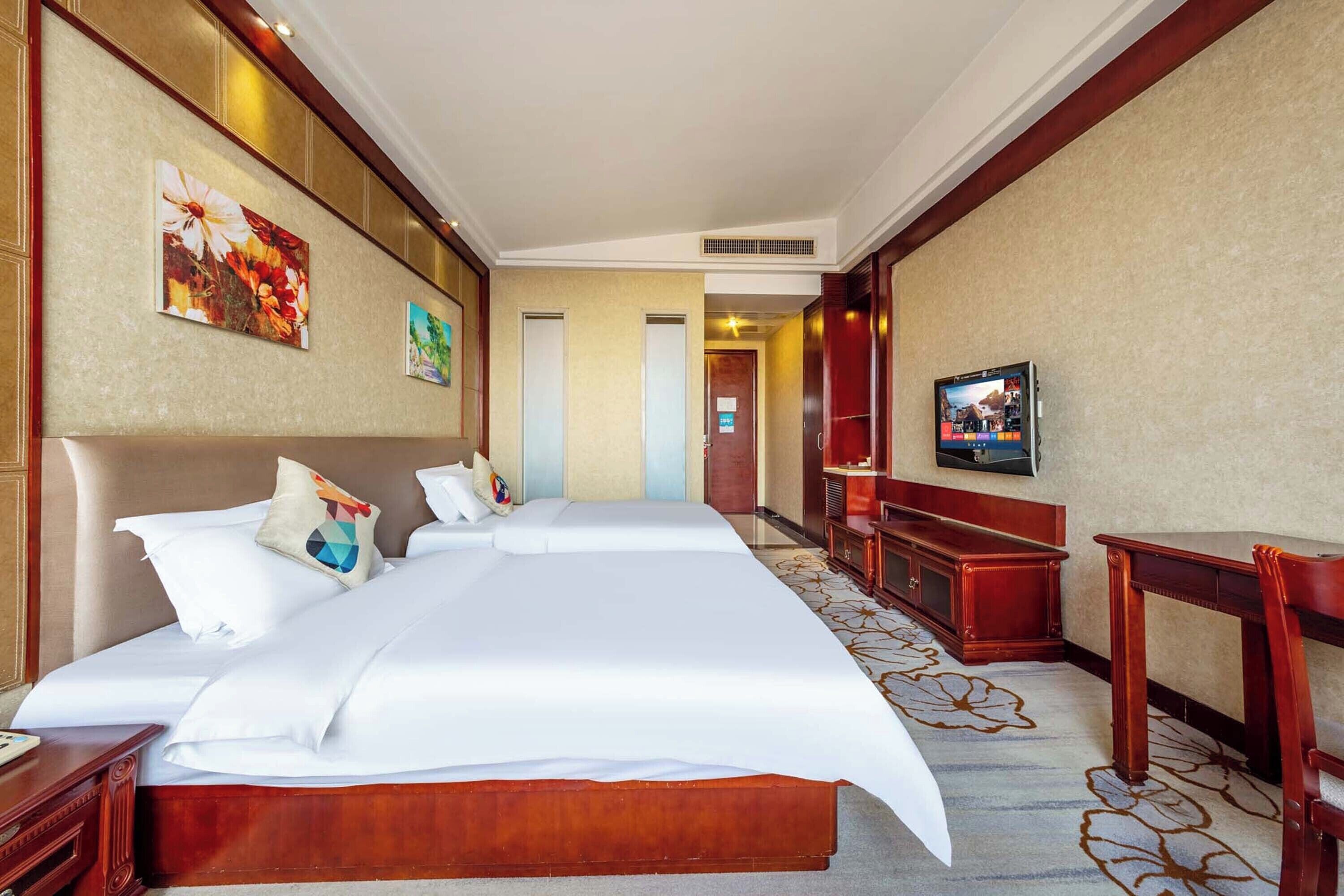 Une chambre d’hôtel avec un grand lit, une télévision, un bureau et un banc.
