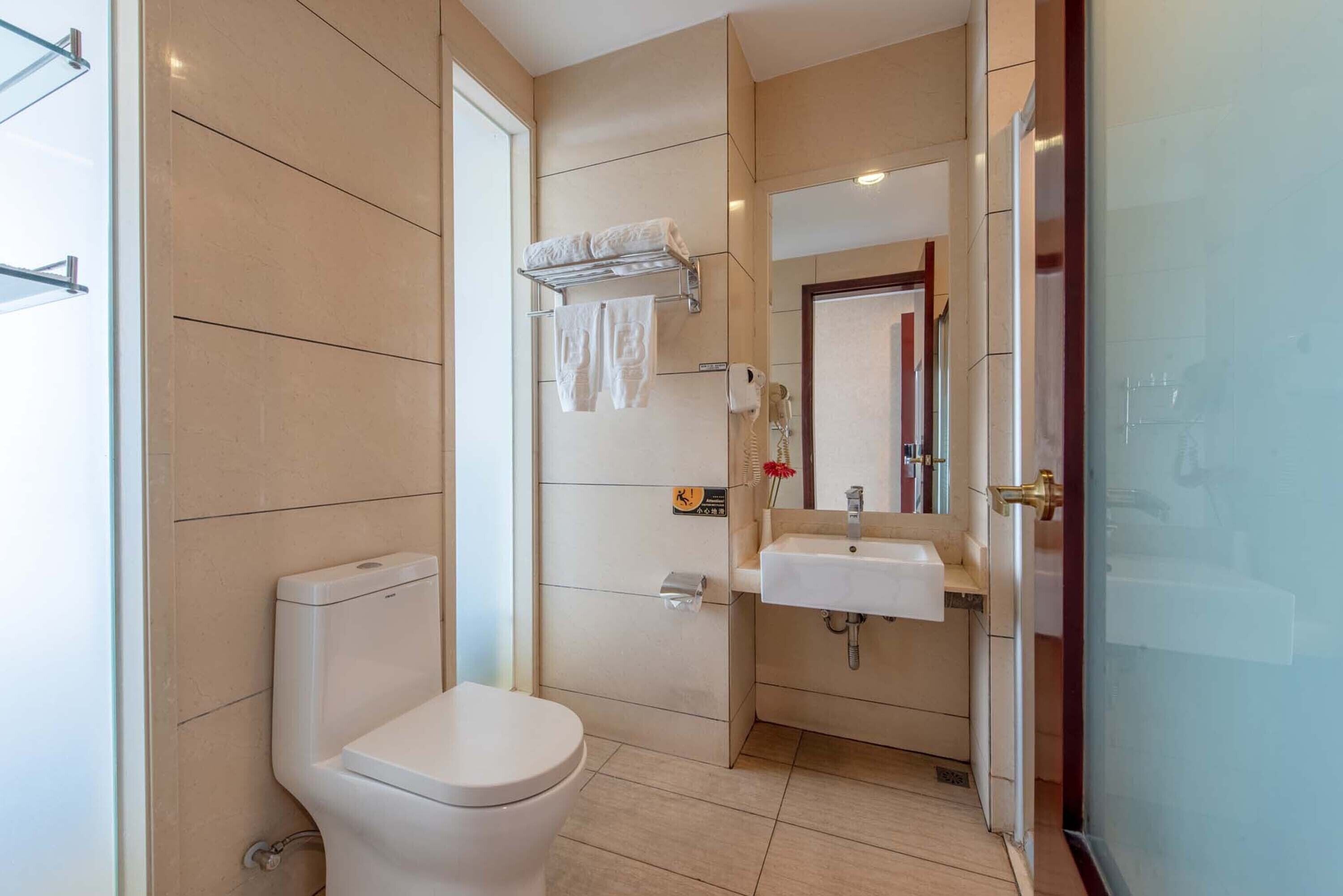 Une salle de bain moderne équipée de toilettes, d’un lavabo et d’une douche à parois de verre.