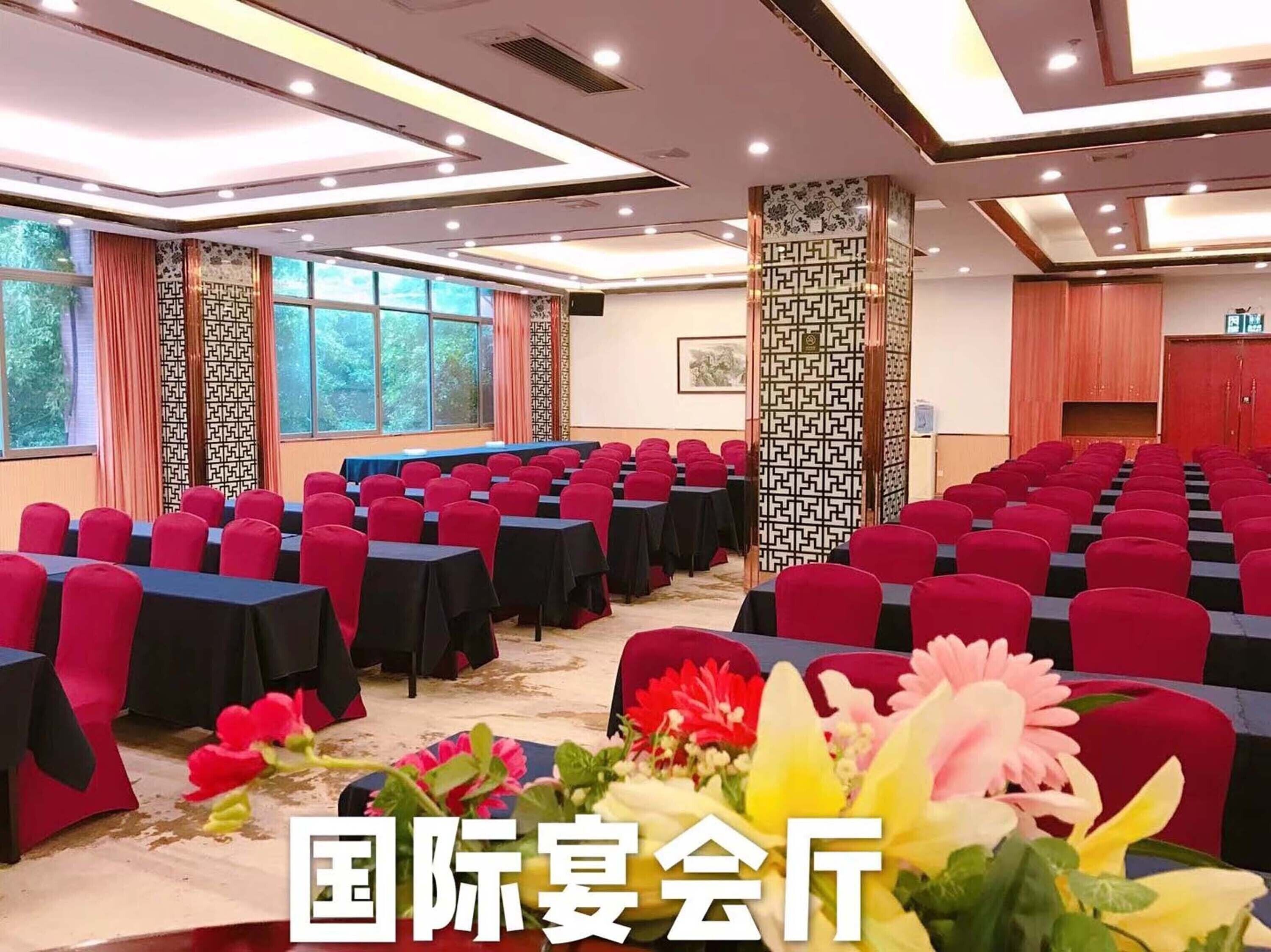 Een congreszaal met rijen tafels en stoelen, grote ramen en decoratieve zuilen.